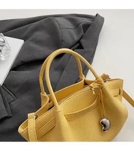 Detail of yellow lychee pattern leather bucket bag with silver bean charm and top handle