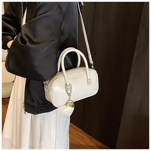 Close-up of white bowling bag with heart charm detail and smooth matte finish