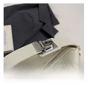 Detail of silver clasp and zipper on white lychee leather handbag with premium finish