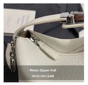 Detailed close-up of cream lychee texture leather with silver metal zipper and pendant