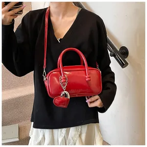 Detail of red glossy patent leather bowling bag with heart charm and brand debossing