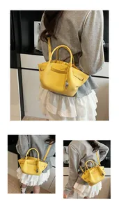 Detail of bright yellow lychee grain leather bag with metal pendant and dual straps