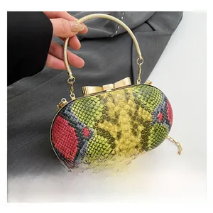 Detail of the snake-patterned evening bag showing its golden bow clasp and circular handle