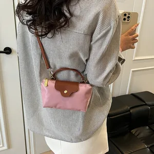 Chic pink nylon tote bag with brown leather handles shown on a model in a modern room