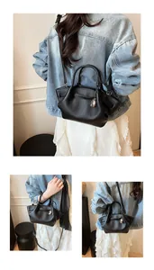 Detailed macro view of black pebble leather wing tote with heart charm and strap