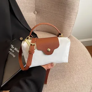 Modern mini tote bag in white nylon and brown leather on a beige fabric chair