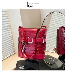 Detail view of a red crocodile embossed bucket bag with glossy patent leather finish