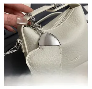 Close-up of beige lychee grain leather texture and silver heart metal charm detail