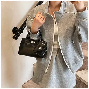 Détail d'un sac à main chic en cuir verni noir avec fermoir argenté et tenue de sport grise