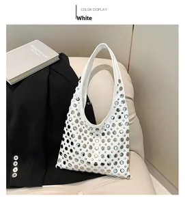 Detail of white faux leather shoulder bag with silver studs and cut-out patterns