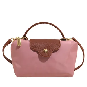 Pink nylon mini dumpling handbag with brown leather flap and golden zipper closure
