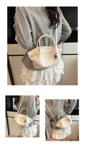 Detailed macro view of white pebble leather tote bag with silver heart charm and handles
