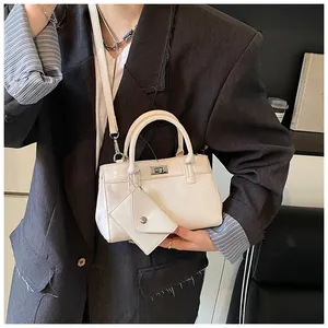 Détail d'un sac carré crème minimaliste avec fermoir argenté et mini breloque