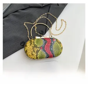Compact snakeskin pattern handbag size comparison with a smartphone and gold chain