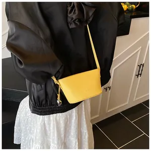Detail of yellow lychee grain leather crossbody bag with a heart metal pendant decoration