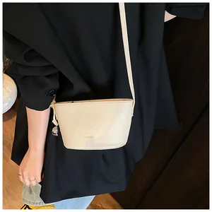 Detail view of the pebbled leather bucket bag in cream with embossed BROBOOM logo