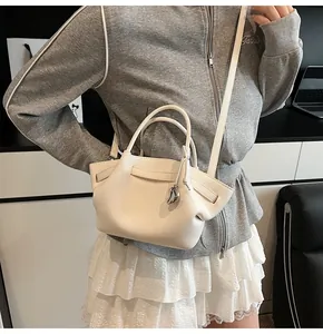 Detail of white lychee texture handbag featuring silver water drop metal pendant decoration