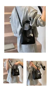 Detail of black lychee grain bucket bag with heart pendant and crossbody strap