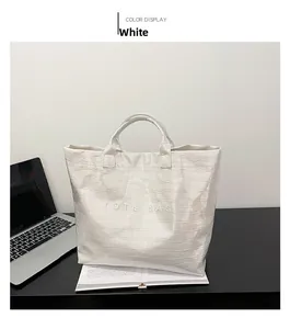 Macro detail of glossy white crocodile pattern leather texture on a large tote bag