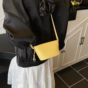 Vibrant yellow litchi leather bucket bag with silver charm shown on a fashion model
