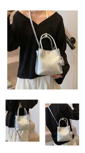 Detailed view of silver textured bucket bag with heart charm and crossbody strap