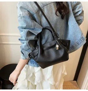Litchi pattern black leather tote bag worn by a model in casual denim outfit