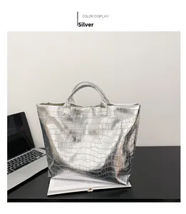 Detailed view of silver crocodile embossed tote bag on desk with metallic texture