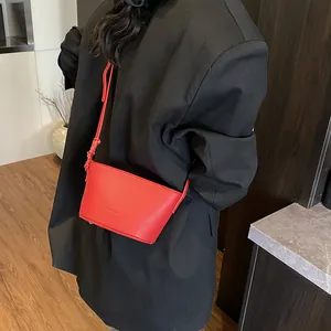 Minimalist red leather bucket bag with knotted shoulder strap shown on black blazer