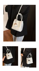 Detail of cream bucket bag featuring lychee texture leather and heart-shaped charm