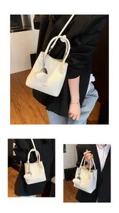 Detail showing white lychee pattern leather bucket bag with top handle and crossbody strap