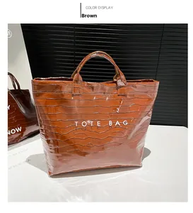 Detail of glossy brown crocodile embossed leather tote bag with white text