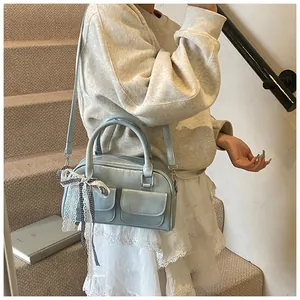 Close-up of light blue PU leather shoulder bag with decorative black and white bow ribbon