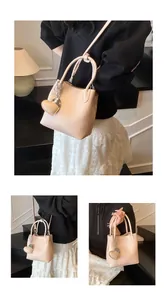 Detail of light apricot bucket bag with lychee texture and heart-shaped pendant charm