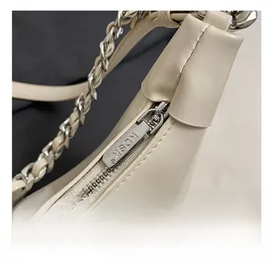 Detailed close-up of a silver zipper with KOSK engraving and woven leather chain strap