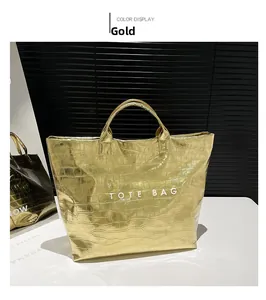 Detail of gold faux leather tote bag with crocodile pattern and TOTE BAG lettering