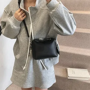 Minimalist black pebble grain square crossbody bag with silver hardware on model