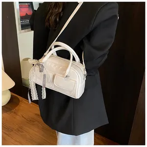Detail of white glossy patent leather bowling bag with lace charms and double front pockets