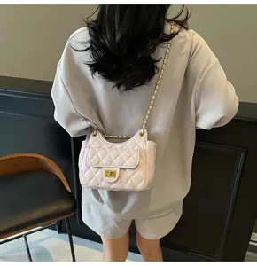 Détail du sac à main matelassé blanc avec chaîne dorée porté sur l'épaule