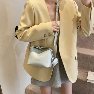 Light grey pebble leather square crossbody bag with heart charm shown on model
