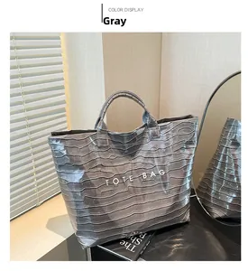 Detail of grey crocodile pattern glossy patent leather tote bag with white text printing