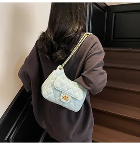Détail d'un sac bandoulière matelassé bleu clair avec chaîne dorée et fermoir rotatif