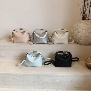 Minimalist square crossbody bags in five colors on stone steps with decorative vase