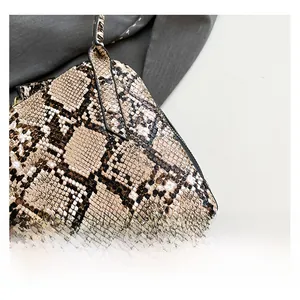 Détail du sac à main en cuir gaufré serpent avec rivets métalliques dorés sur le fond