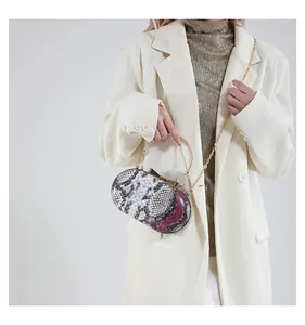 Detail of the snakeskin pattern clutch bag with gold ring handle and chain strap