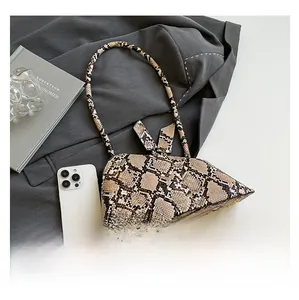 Détail du sac à main imprimé serpent avec nœud et smartphone pour comparaison de taille