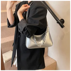 Silver metallic hobo bag with chunky chain strap worn by a model in a modern urban setting