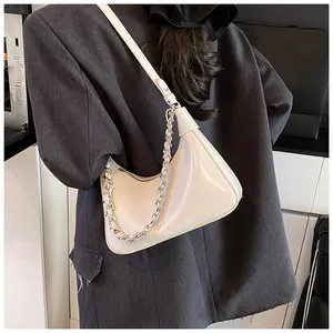 Detail of a creamy white crescent Hobo bag with silver chain strap on a model wearing grey suit
