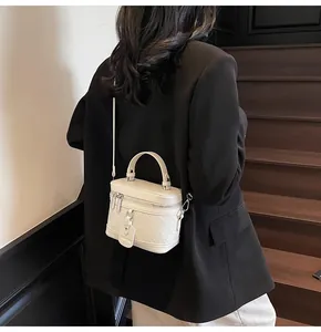 Detailed view of cream white quilted bucket bag featuring top handle and slim strap