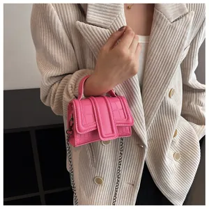 Close-up of pink mini chain bag with crocodile texture on model's beige corduroy suit