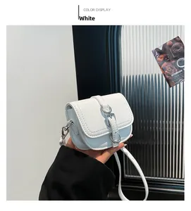 Detail einer weißen Mini-Umhängetasche aus glänzendem Leder mit Metallschnallen-Dekor